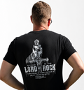 A man viewed from behind wearing a black t-shirt with a large white graphic print on the back. The graphic features a soldier statue and the text 'BLESSED BE THE LORD MY ROCK' with a Bible verse below.