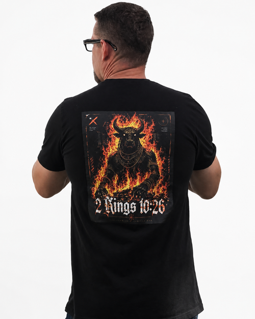 A man viewed from behind wearing a black t-shirt with a large graphic print on the back. The graphic features a fiery, horned demon figure in orange and yellow flames, with the text '2 Kings 10:26' in a gothic font at the bottom.