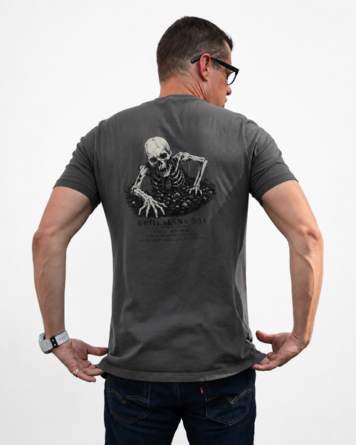 A man wearing a dark gray t-shirt with a large skeleton graphic on the back, shown from behind against a light gray background.